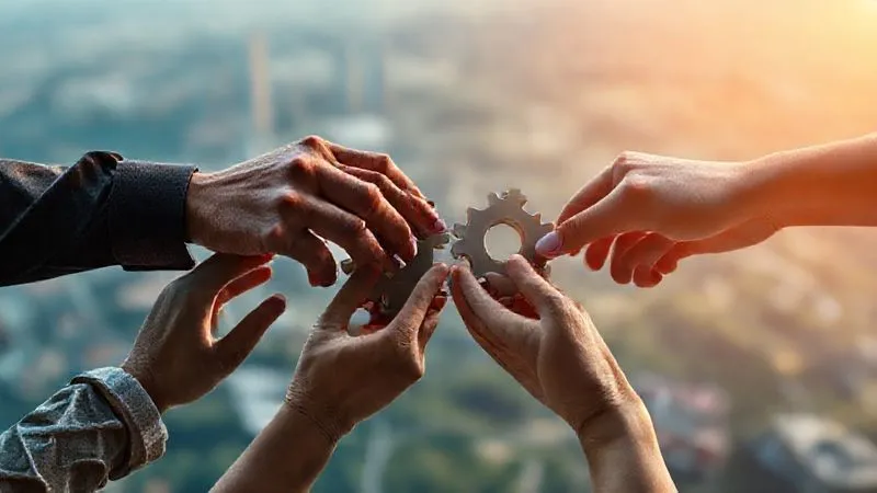 A photorealistic image of diverse hands from different backgrounds (represented by subtle cultural cues) interlocking gears or puzzle pieces, symbolizing collaborative diplomacy and building shared understanding in a complex global context. The background features a blurred, futuristic digital landscape. Cinematic lighting, sharp focus, 8K hyper-detailed.