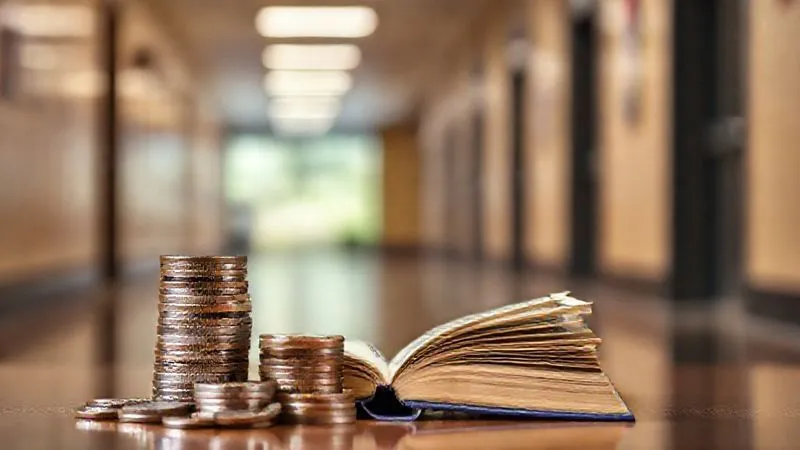 A photorealistic image of a stack of coins and dollar bills next to a small, open book titled 'Benefits Guide', with a blurred background of a modern school hallway. The lighting is warm and professional, emphasizing financial planning and stability. Shot on a high-end DSLR, 8K hyper-detailed, sharp focus on the money and book.